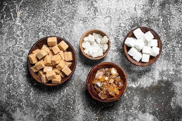 Different kinds of sugar in bowls. On a rustic background.