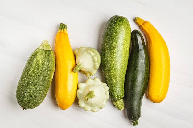 Generi differenti di zucchini su fondo bianco, vista superiore, spazio della copia. concetto di mangiare sano e pulito.