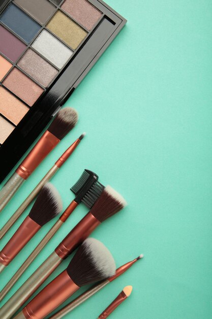 Different luxury makeup products on mint background, flat lay. Top view. Vertical photo