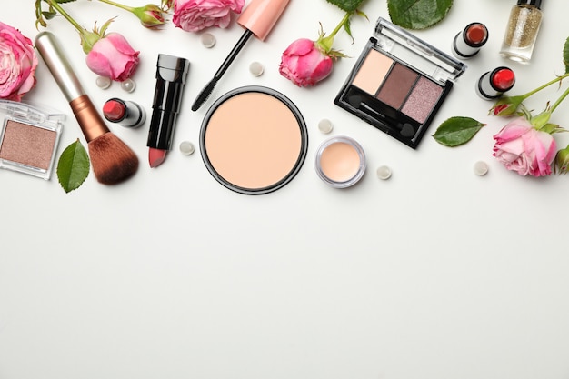 Different makeup cosmetics and flowers on white background