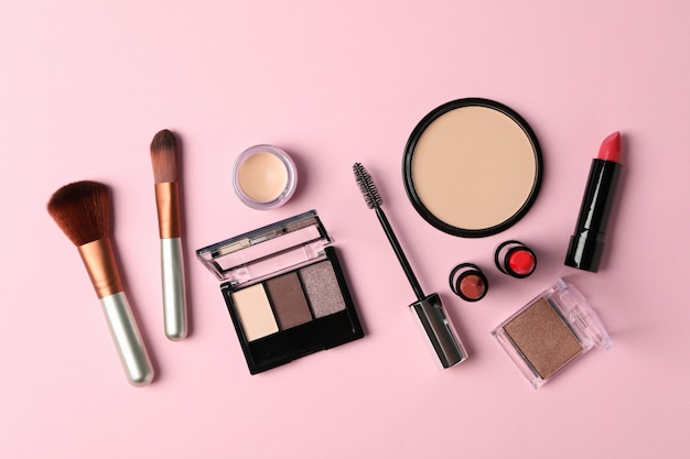different makeup cosmetics on pink background. female accessories