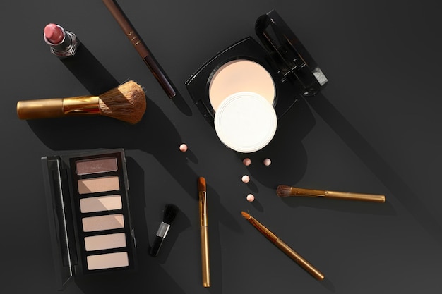 Different makeup items on a dark background top view