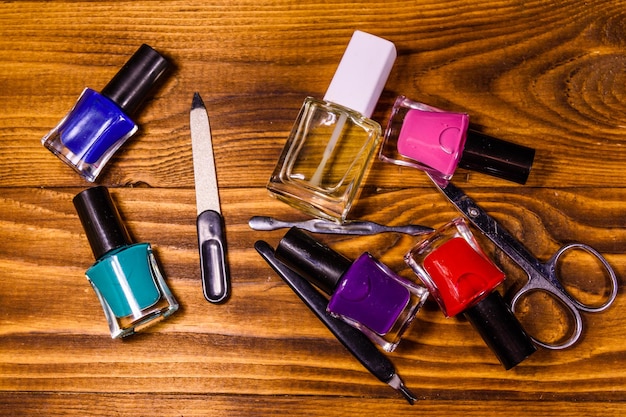 Different manicure tools and nail polishes on wooden table Top view