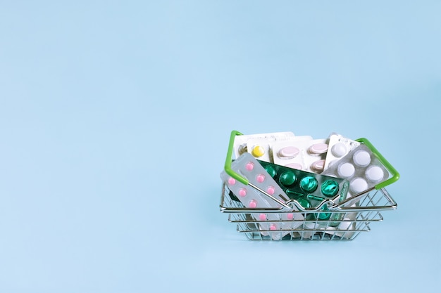 Different medicine blisters in the stainless steel basket on blue . Medicine  close up.