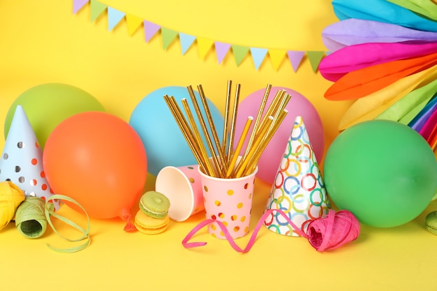 Different multicolored birthday accessories on yellow background