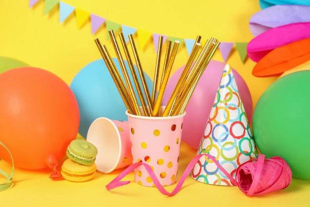 Different multicolored birthday accessories on yellow background