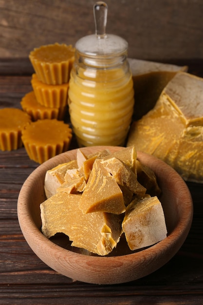 Different natural beeswax blocks and honey on wooden table