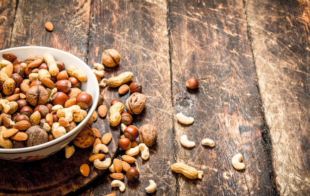 Different nuts in a bowl on wooden background