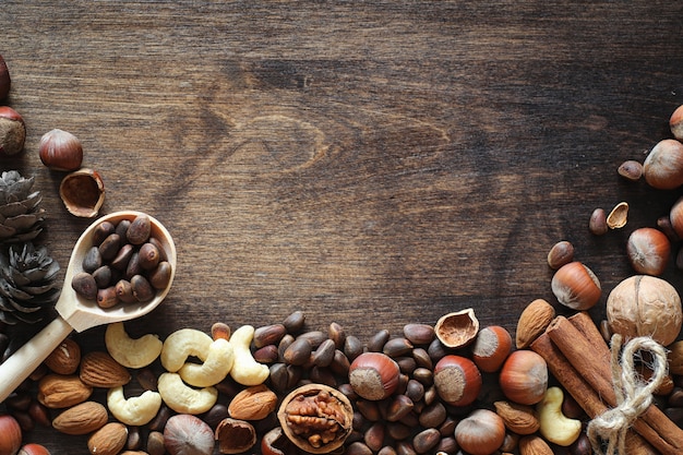 Different nuts on a wooden table. Cedar, cashew, hazelnut, walnuts and a spoon on the table. Many nuts are inshell and chistchenyh on a wooden background