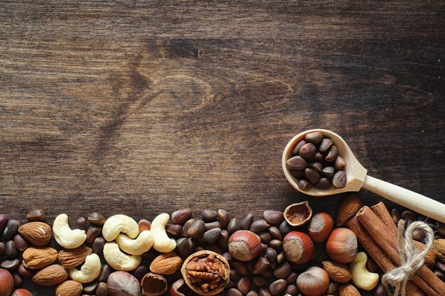 Different nuts on a wooden table. Cedar, cashew, hazelnut, walnuts and a spoon on the table. Many nuts are inshell and chistchenyh on a wooden background