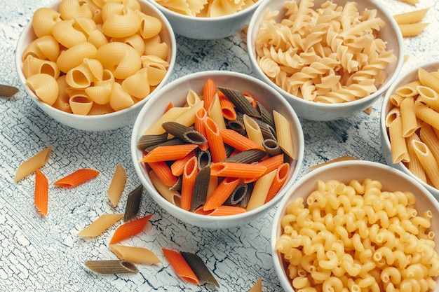 Different pasta types in bowls on the table.