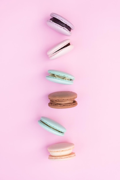 Different pastel colors pastry macaroons top view on a pink background
