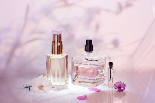 ピンクの背景に植物とさまざまな香水瓶とサンプラー