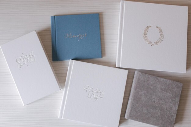 Different photobooks and photoboxes on white wooden table textile and leather