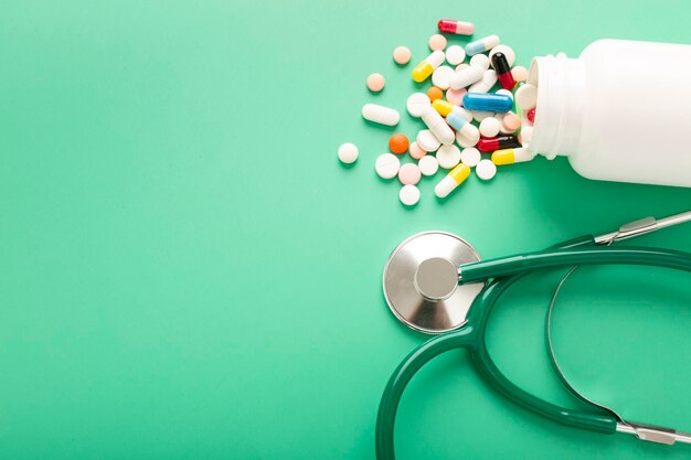 Different pills and antibiotics are spilled on the table from a medical jar