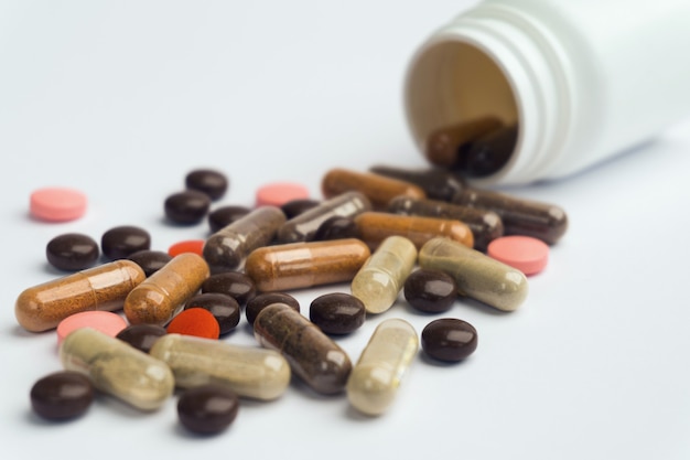 Different pills and capsules scattered on a white background.