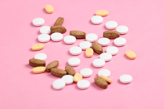 Different pills on a pink pastel closeup