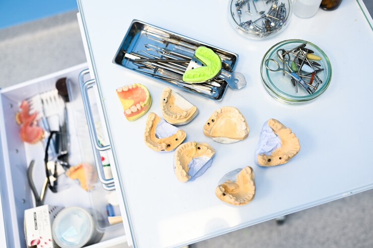 Photo different professional dental equipment, instruments and tools in a dentists stomatology office clinic on a white background. silicone cast of the jaw.