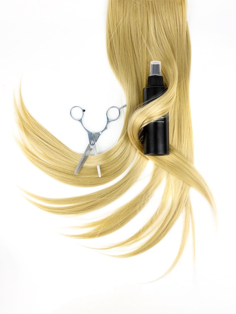 Different professional hairdresser tools Hairdresser's scissors with hair spray and strand of blonde hair on white background flat lay Hair care spa concept