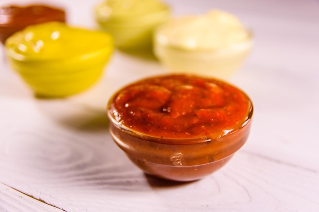 Different sauces in glass bowls on wooden table