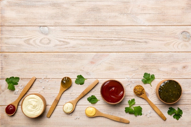 Different sauces in spoons on table background flat lay top view