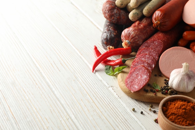 Different sausages and spices on wooden background, space for text