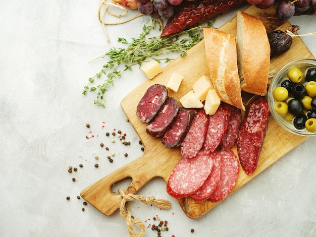 Different sausages with cheese, grapes and olive. Sliced Salami in rustic style