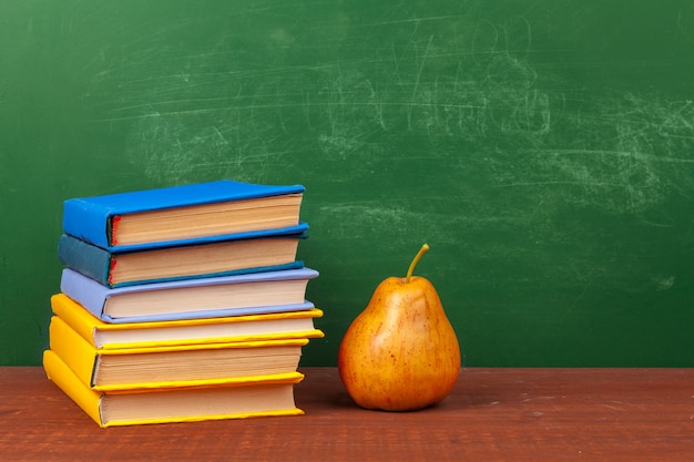 Different school supplies,  books and pear on wooden table