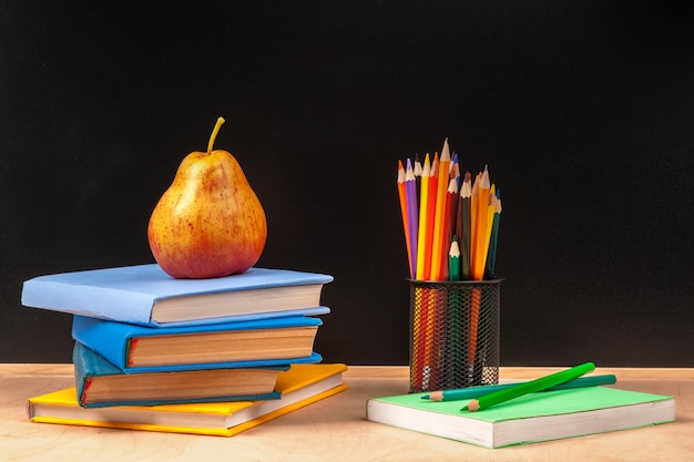 Different school supplies,  books and pear on wooden table