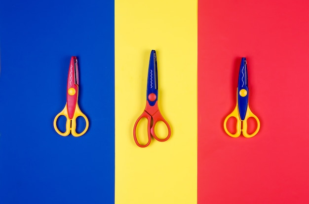 Различные ножницы для детского творчества на фоне красочной бумаги.