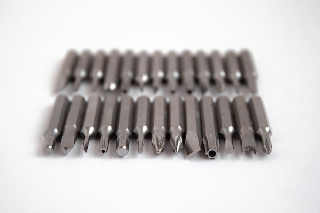 Different screwdriver tips are placed in two rows on a white background