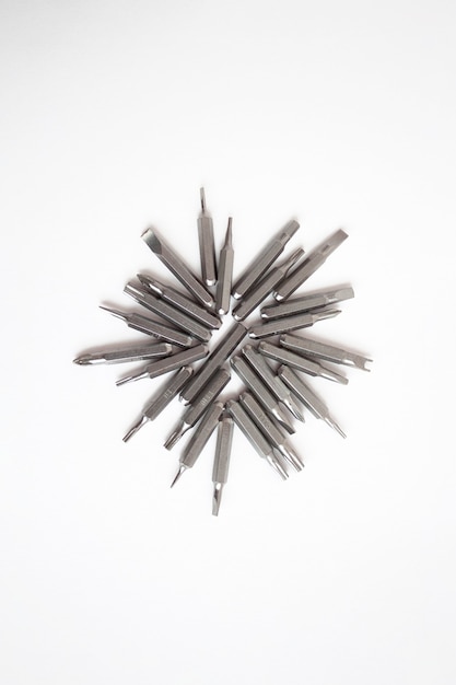 Different screwdriver tips lie on a white background in the form of a sun.