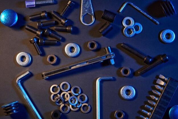 Different screws, nuts, washers, screwdrivers on black table. Hardware tools and metal bolts, nuts, and washers.