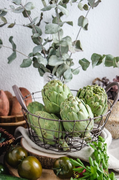 Different seasonal vegetables and artichokes in a metal basket