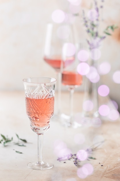 Different shapes of glasses of rose wine on light background.
