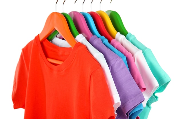 Different shirts on colorful hangers on white background