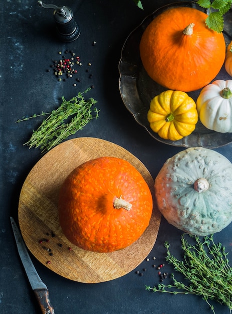 Different in size and color of the pumpkin on dark table.  Top view