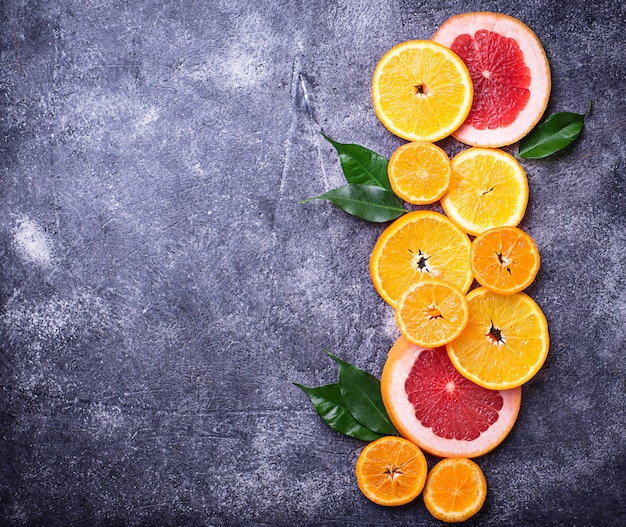 Different sliced citrus on dark concrete background