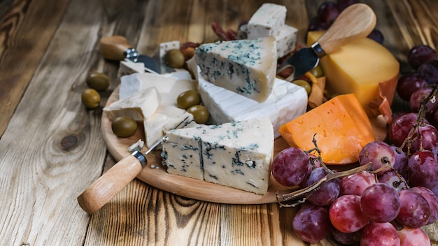 Foto diversi tipi di formaggio e uva su legno