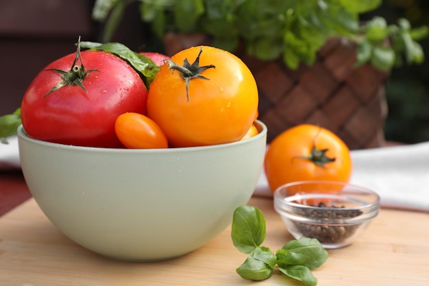 Different sorts of tomatoes and basil on wooden table