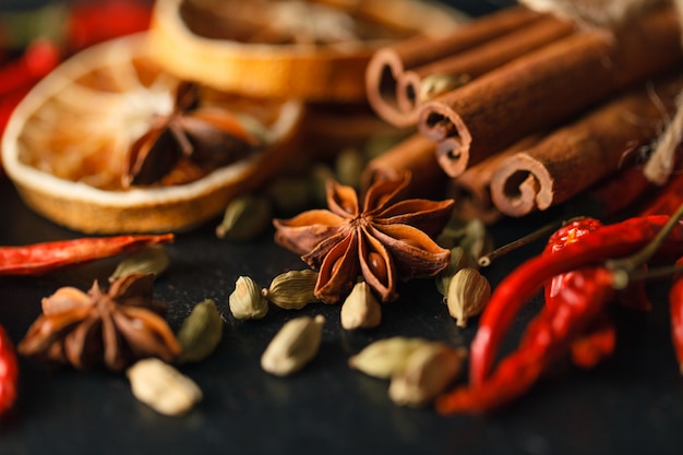 Different spices and herbs on a black slate.