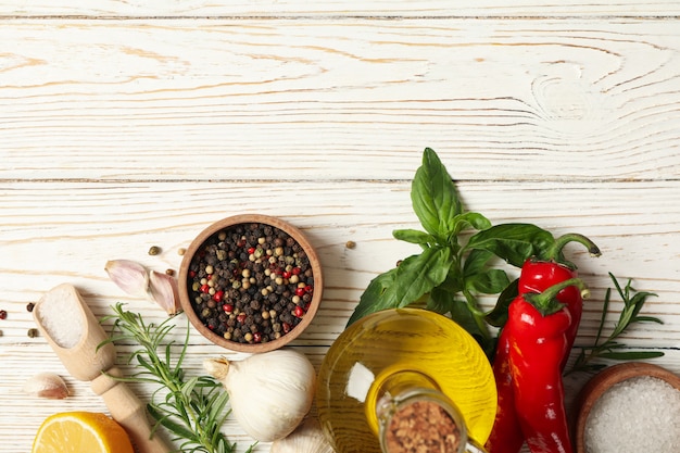 Different spices and herbs on white wooden background, top view