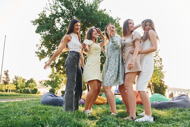 in different stylish clothes group of young people have a party in the park at summer daytime