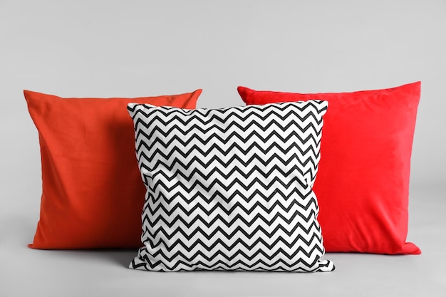 Different stylish soft pillows on grey background