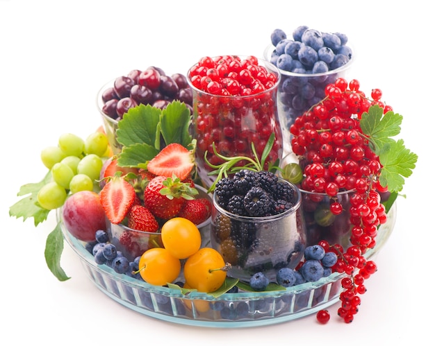 Different summer berries red currant, gooseberry, raspberry in glass trays. sorted by type.