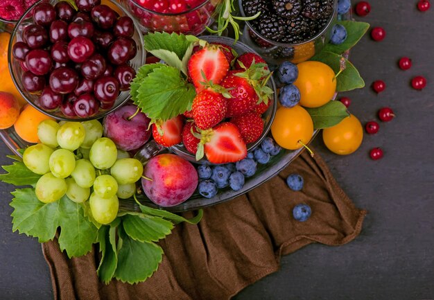 Different summer berries red currant, gooseberry, raspberry in glass trays. sorted by type.