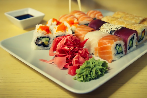 Different sushi rolls with soy sauce on wooden desk