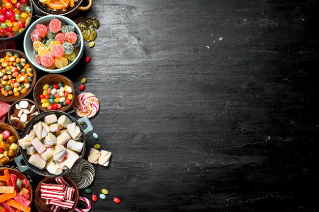 Different sweet candy, jelly and candied in a bowl. On the black chalkboard.