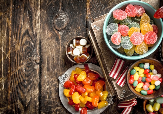 Different sweet candy, jelly, marshmallows and candied fruits. On a wooden table.