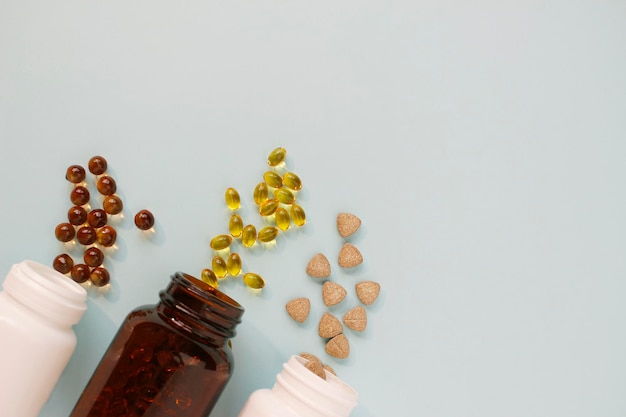 Различные таблетки, капсулы, пилюли разбросаны из банки на светлом фоне Концепция здоровья Минимализм